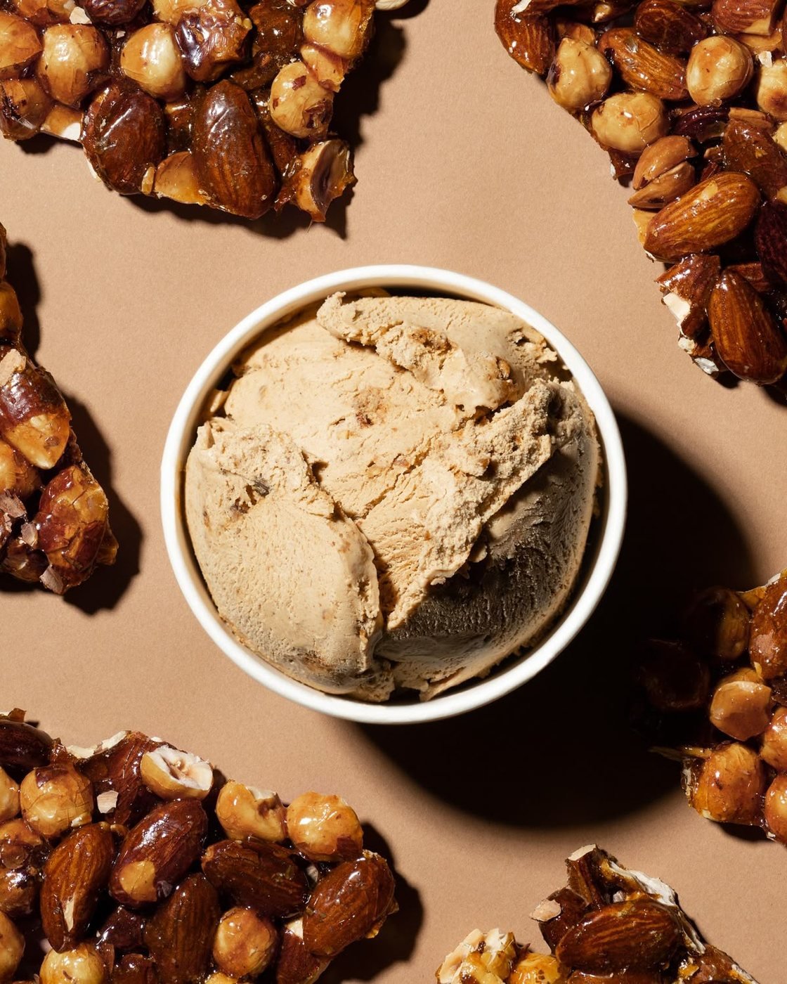 A cup of butter pecan ice cream surrounded by house-made nut brittle
